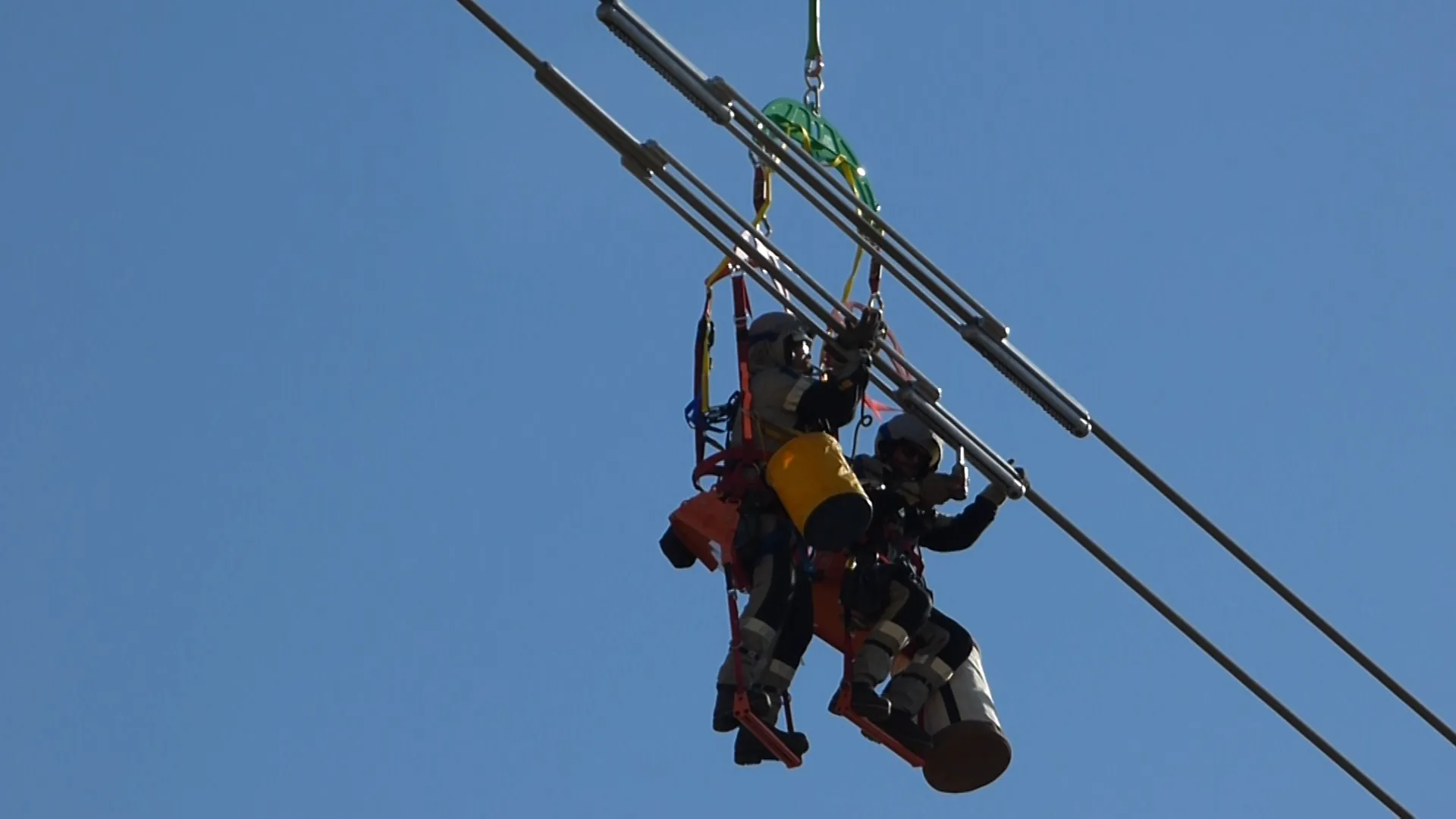 Two lineworkers suspended beside transmission conductors during an installation.